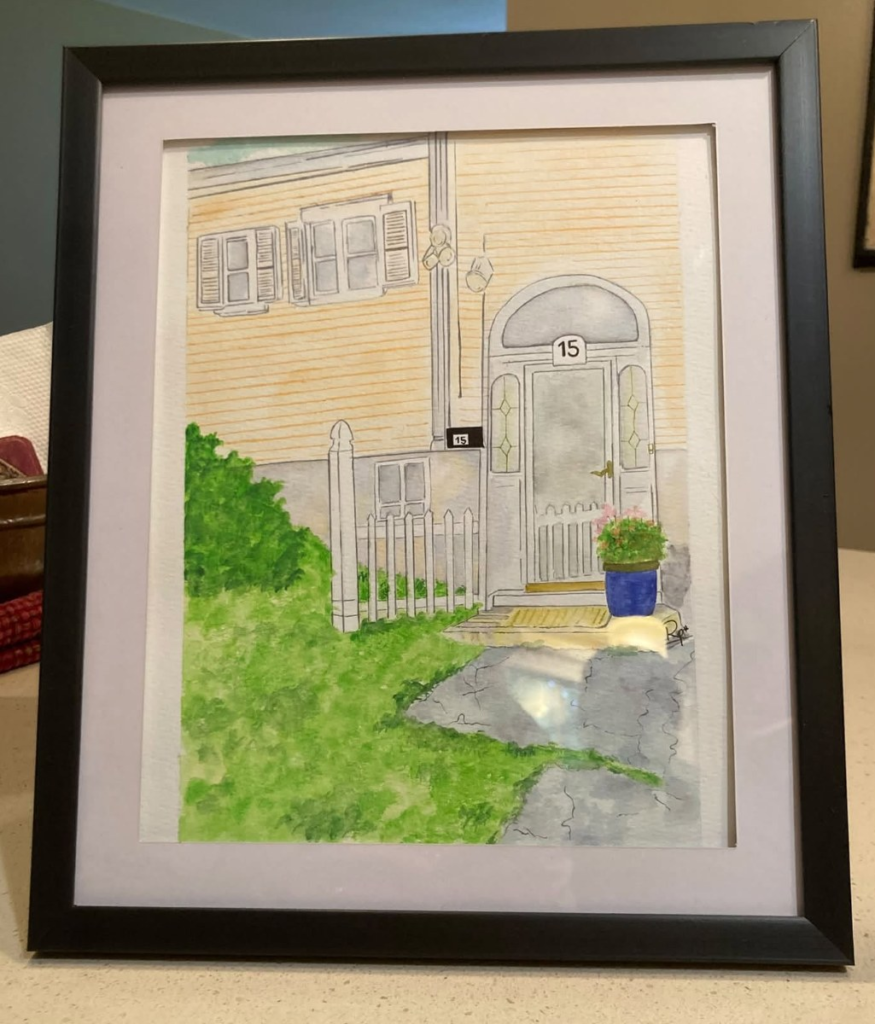 Framed custom watercolor portrait of a home with a white door, picket fence and blue flower pot, painted by Ruth